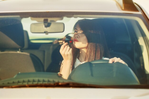 Photo woman putting lipstick in the car before date