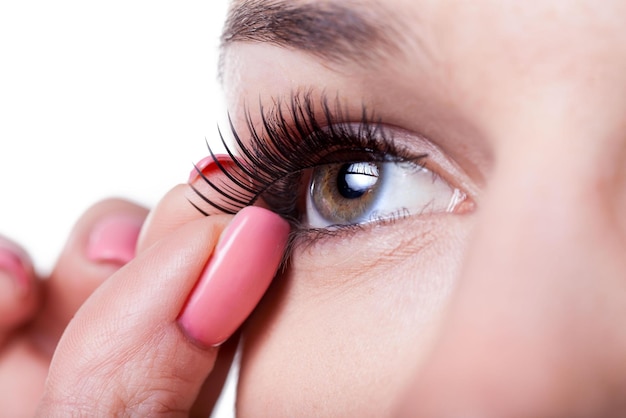 A woman putting mascara on her eye