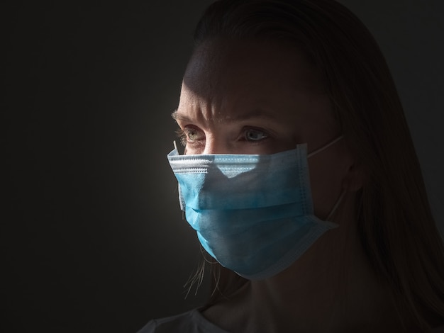 A woman putting on a medical disposable mask to avoid contagious viruses