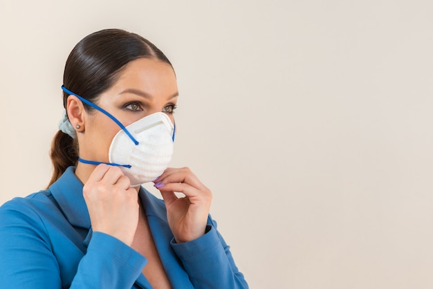 Женщина надевает медицинскую маску на лице