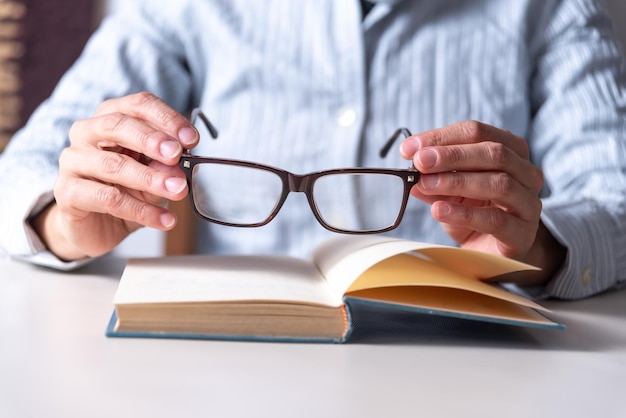Фото Женщина надевает очки, чтобы начать читать, копировать пространство, читая концепцию образования близорукого зрения, выборочный фокус, чтение, выборочный фокус