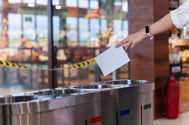 Woman putting paper into trash bin in shopping mall