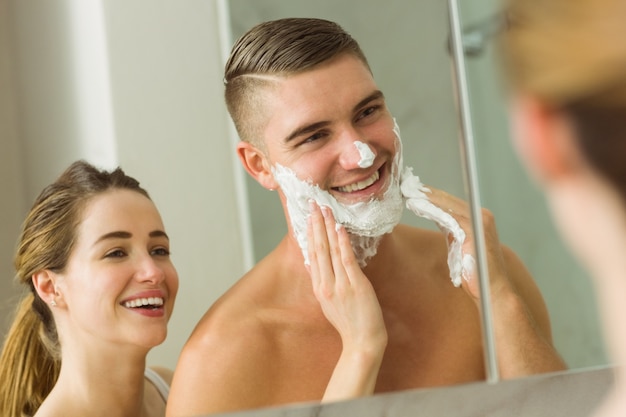 Woman putting shaving foam on boyfriends face