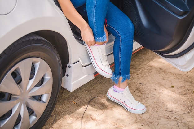 Woman putting on sneakers in car on the side of the road