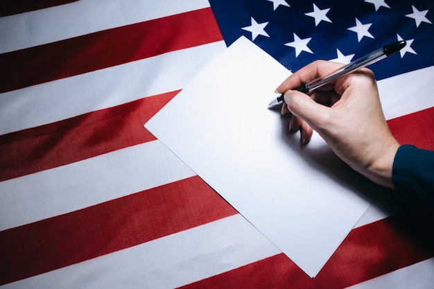 Photo woman putting tick on the paper for vote. political changes in the country. copy space place. elections in the usa. american flag. people voting on ballot.