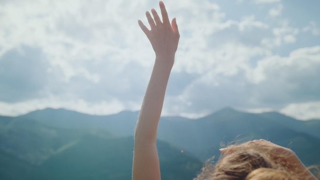 Photo a woman raises her hand in front of a mountain range.