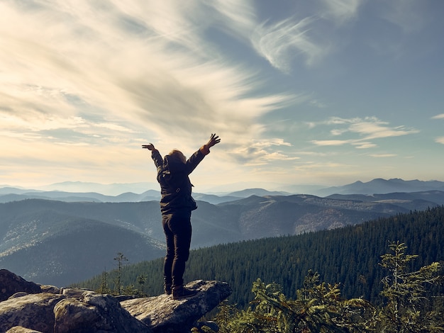 Woman raising hands on mountain.