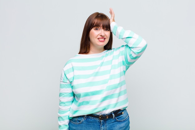 Woman raising palm to forehead thinking oops