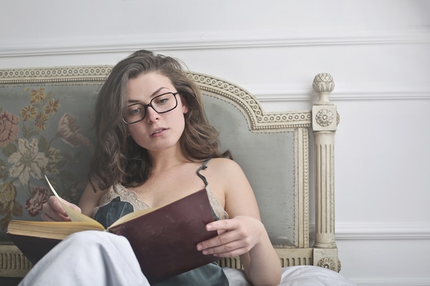 Фото Женщина читает книгу в спальне