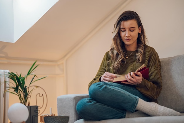 写真 自宅のソファに座って本を読む女性