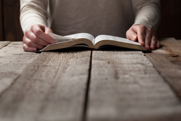 Woman reading the bible in the darkness over wooden table