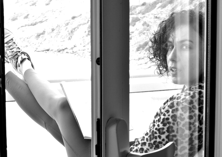 Photo woman reading a book at the balcony stares sensually to the camera