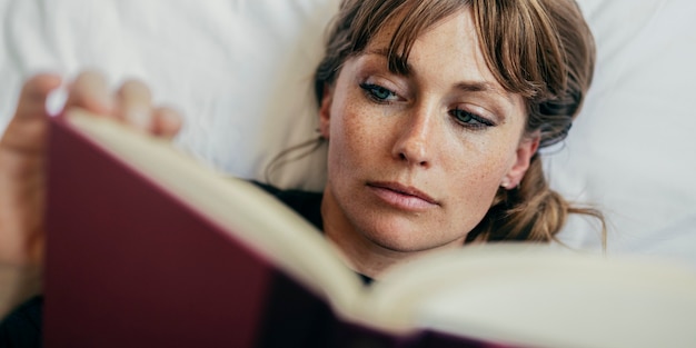 Woman reading a book on a bed during coronavirus quarantine