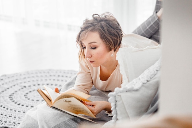 Woman reading book on bed at home