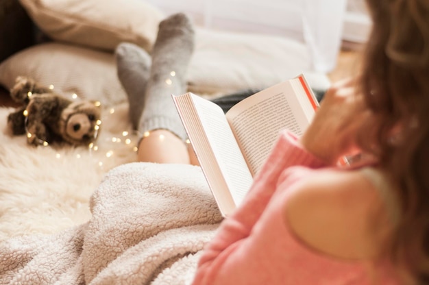 Foto donna che legge un libro a letto a casa