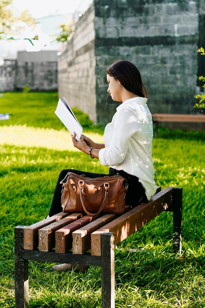 公園のベンチで本を読んでいる女性