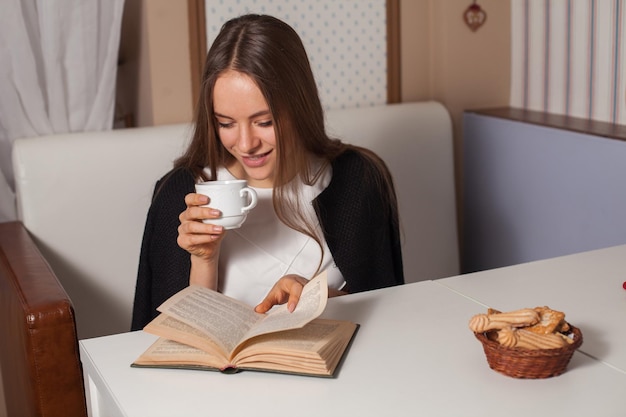 Woman reading book in cafe and drinking tea