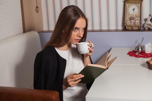 Woman reading book in cafe and drinking tea