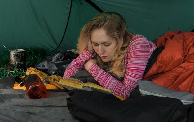 Woman reading book in camp tent