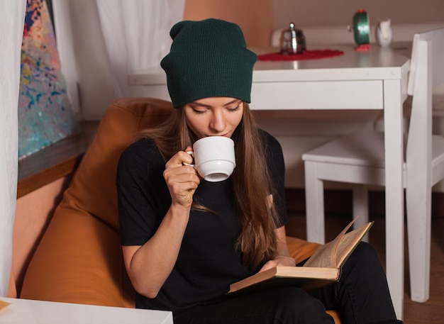 Woman reading book and drinking tea in cafe