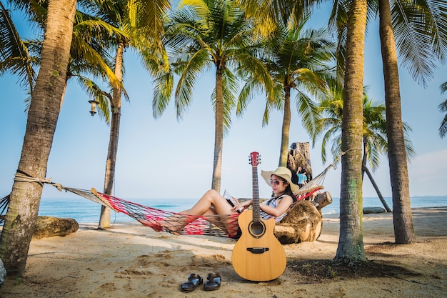 A woman reading a book on hammock under coconut tree during holiday. 