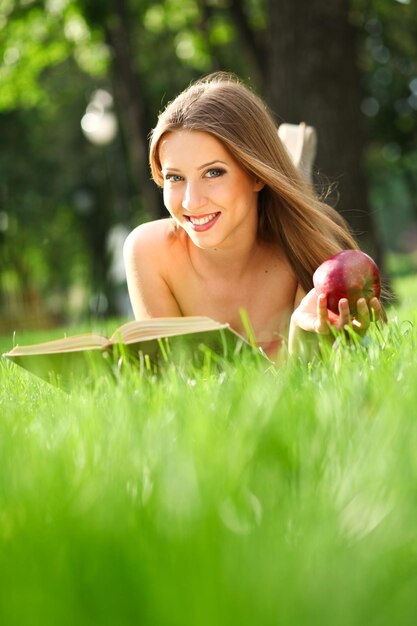 Woman reading book in the park on the grass