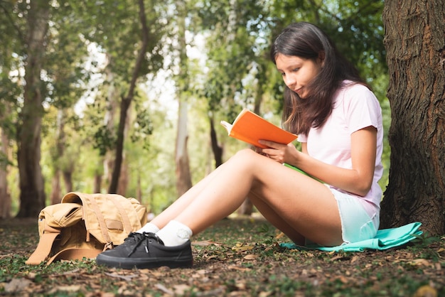 Woman reading book and resting in forest