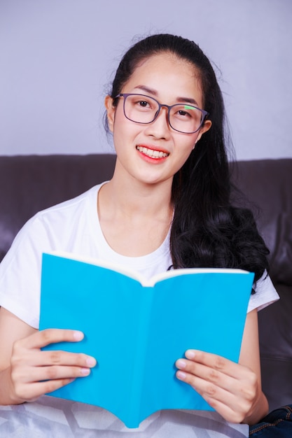 woman reading a book on sofa at home