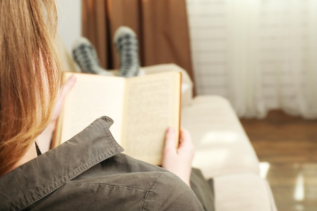 Woman reading book on sofa in room