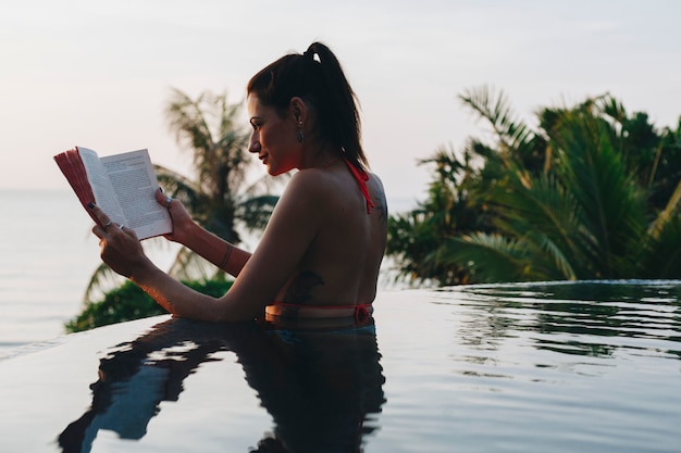 Woman reading a book in the swimming pool