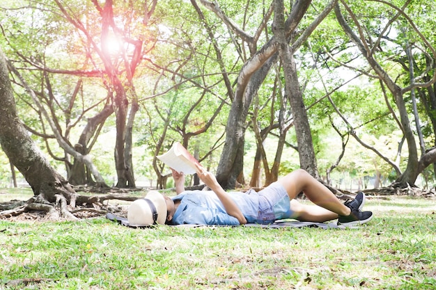 Woman reading book while lying on field in park