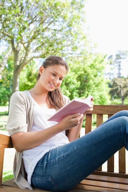 Woman reading a book while sitting on a bench