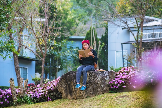 Woman reading book while sitting on stone