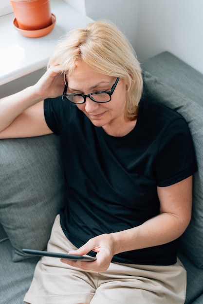 Woman reading e-book sitting on sofa at home