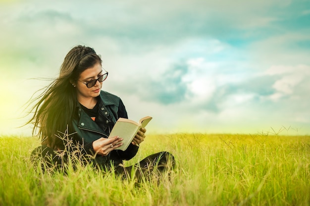 Woman reading in the field, girl reading a book with copy space