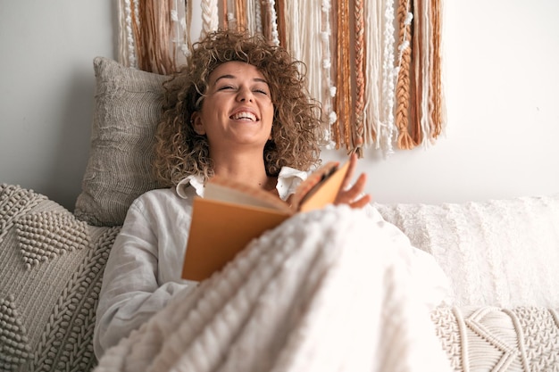 Photo woman reading funny book on bed