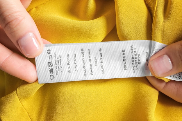 Фото Женщина читает инструкцию на этикетке одежды крупным планом