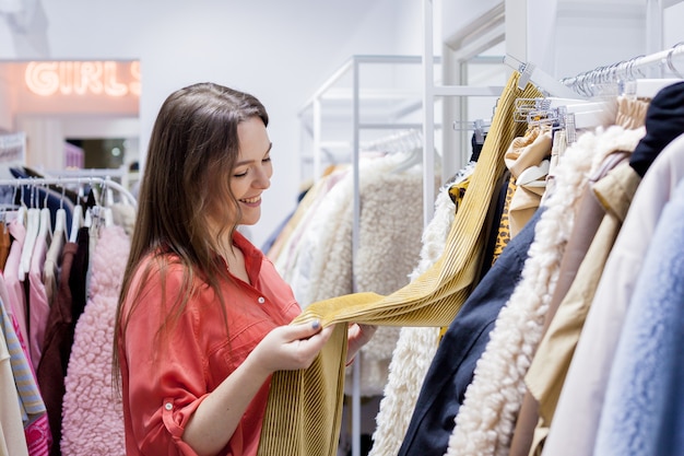 Woman reading the label and buying red sweater at mall