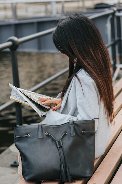 woman reading magazine on bench at city waterfront photo