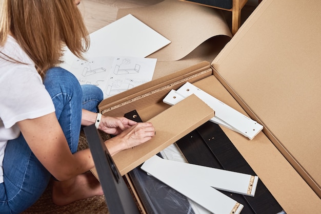 Woman reading manual instruction to assemble furniture in the living room