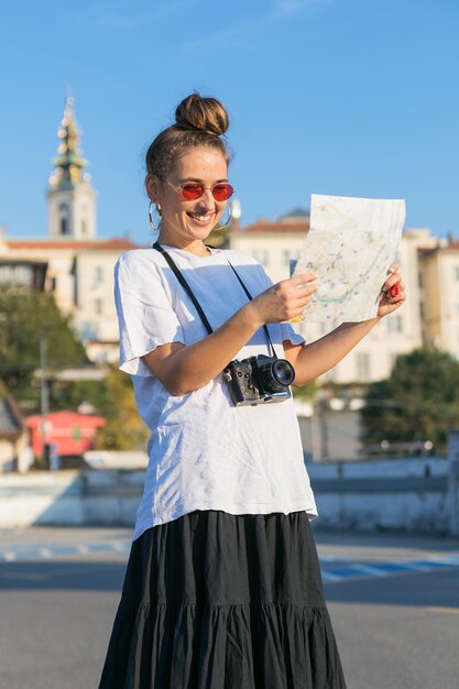 Photo woman reading map while standing against blue sky in city