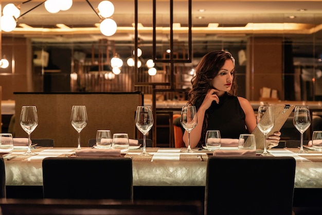 Photo woman reading menu while sitting at table in restaurant