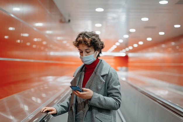 Woman reading a message standing on a subway platform