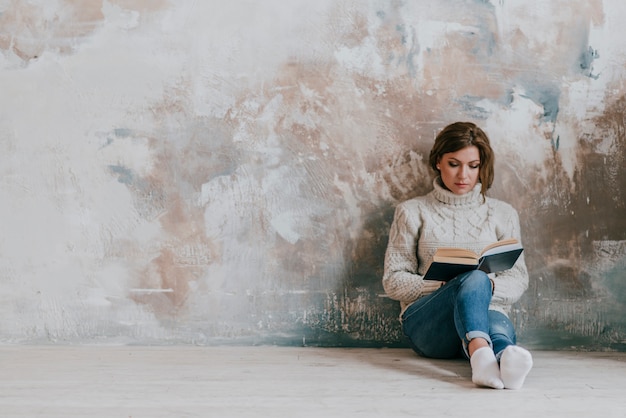 Woman reading near wall