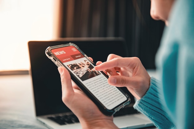 Woman reading news or articles in a mobile phone screen application at home.