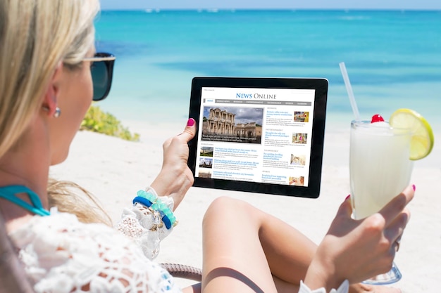 Woman reading news on tablet while relaxing on the beach