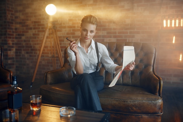 Woman reading newspapar with whiskey and cigar