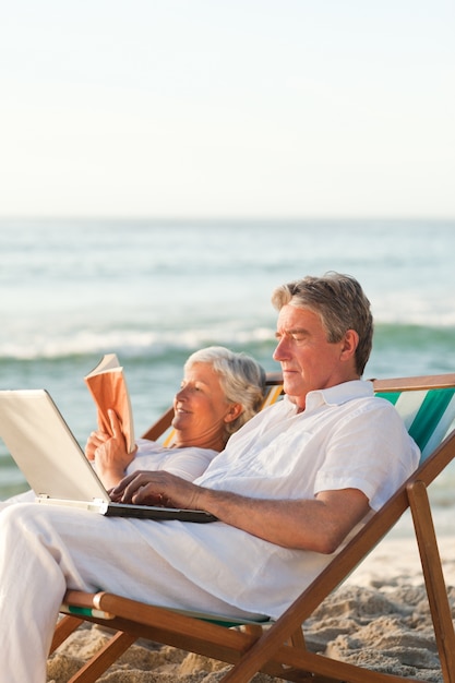 Woman reading while her husband is working on his laptop