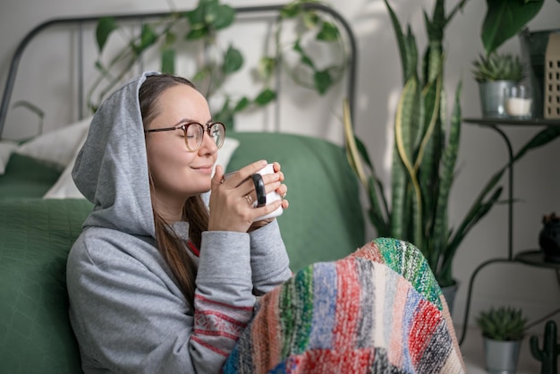 Photo a woman reads a book in a cozy interior with tropical flowers