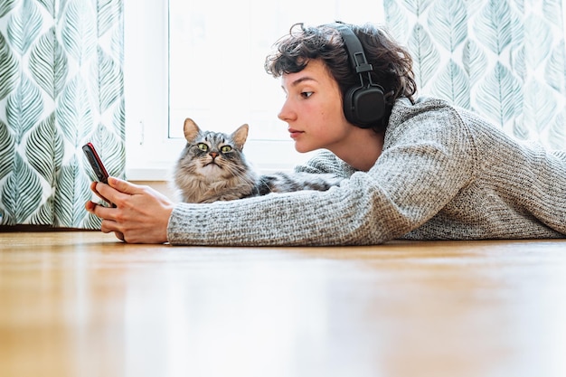 여자는 바닥에 고양이와 함께 책을 읽습니다.